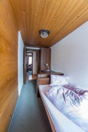 A narrow hallway leading to a bedroom with a bed, a desk, and a chair. - Maria Appartement/Fewo 4-Bettwohnung Nr. 5 by Interhome (Saas-Fee)