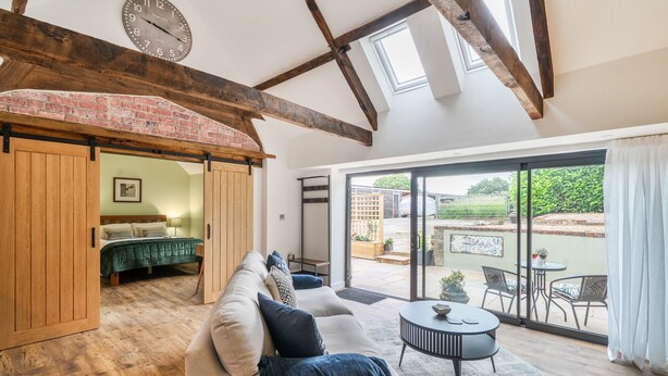 Une pièce spacieuse avec un lit en mezzanine, un canapé et un coin repas offrant une vue sur le jardin.