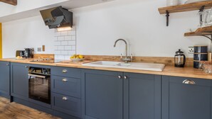 Une cuisine moderne dotée d’un plan de travail en bois, d’un four encastré, d’un évier et d’une machine à café.
