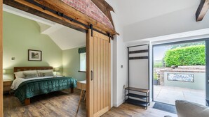 Une chambre à coucher avec un lit, une porte en bois, un banc et une vue sur l’extérieur.