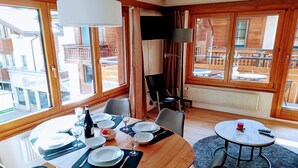A dining area with a table set for two, a TV, and a view of the outside. - Cabane 3 Appartement/Fewo Holiday-Schöner Wohnen by Interhome (Saas-Fee)