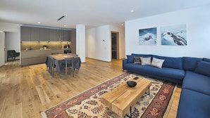 A modern living room with a blue sofa, a wooden coffee table, and a dining area with a table and chairs. - Silberdistel EG Appartement/Fewo Appartement/Fewo by Interhome (Saas-Fee)