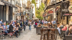 A bustling outdoor café area with outdoor seating and a cobblestone street.