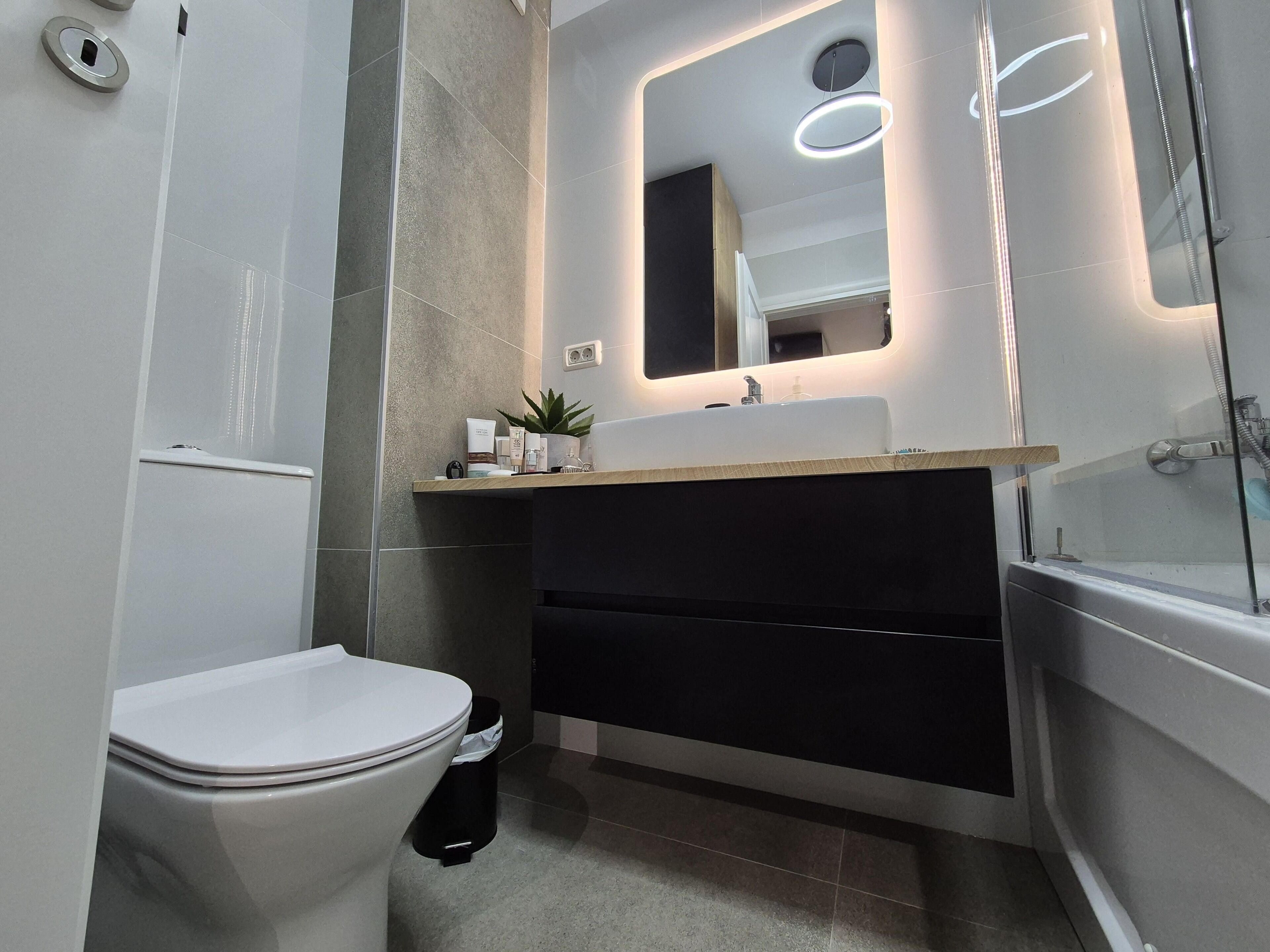Een moderne badkamer met toilet, wastafel en bad.