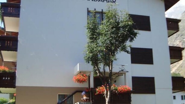 Ein Gebäude mit der Beschriftung 'KANDAHAR', einer Treppe und einem kleinen Baum mit Blüten.