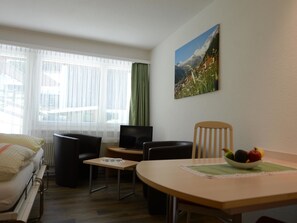 A hotel room with a bed, two chairs, a small table, a television, and a painting on the wall. - Kandahar Appartement/Fewo 2-Bettwohnung Nr. 1 by Interhome (Saas-Fee)