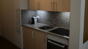 Eine Küche mit Holzausstattung, einer Granit Arbeitsplatte, einer Spüle mit zwei Becken und einem eingebauten Backofen.