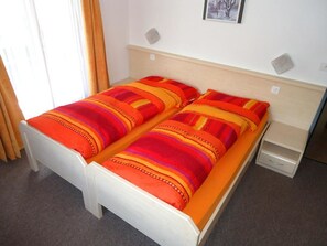 Ein Doppelbett mit gestreifter Bettwäsche, ein Nachttisch und eine kleine Kommode.