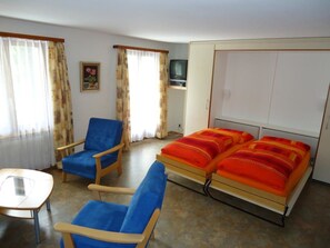 A room with a bed, two chairs, a small table, a television, and a wardrobe. - Haus Rio Appartement/Fewo 4-Bettwohnung Nr. 4 by Interhome (Saas-Fee)