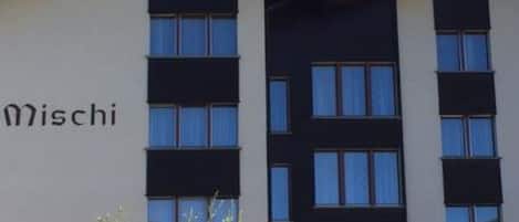 A modern building with a flat roof, multiple windows, and a sign that reads 'Mischi'.