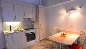 A compact kitchen with a dining area, including cabinets, a sink, an oven, and a table with chairs. - Mischi Appartement/Fewo 2-Bettwohnung Nr. 15 by Interhome (Saas-Fee)