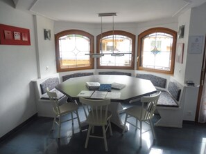 Een eetruimte met een ronde tafel, vier stoelen en inbouwbanken langs de muren.