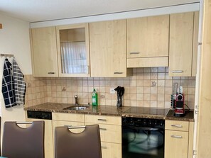 A kitchen with wooden cabinets, a granite countertop, a dishwasher, and a coffee machine. - Bergröschen Appartement/Fewo 5-Bettwohnung by Interhome (Saas-Grund)
