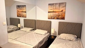 Ein Hotelzimmer mit drei Betten, jeweils mit Kopfstütze und Nachttischlampe.