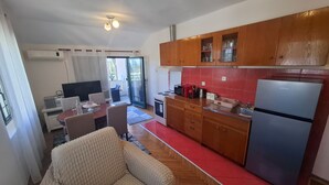 Eine kompakte Küche mit Holzausstattung, einem Kühlschrank, einer Mikrowelle und einem Essbereich mit Tisch und Stühlen.