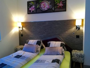 Una cama doble con una colcha estampada, dos almohadas y dos lámparas de pared.