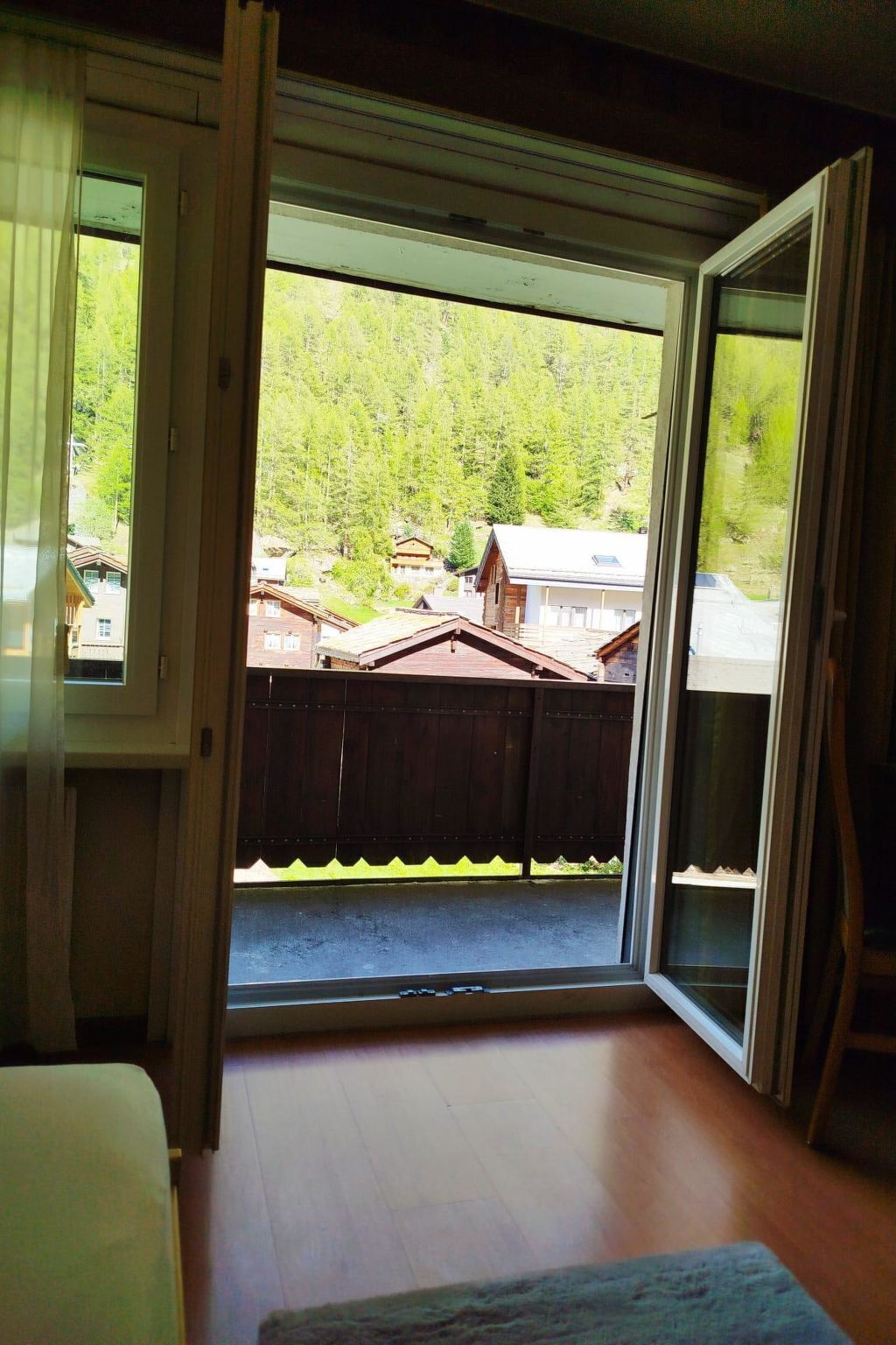 A room with a large sliding glass door leading to a backyard with a wooden fence and houses in the background.