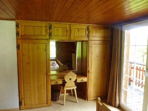 Ein Zimmer mit Holzboden, einem Schreibtisch, einem Stuhl und einem Fenster mit Blick auf einen Holzzaun.