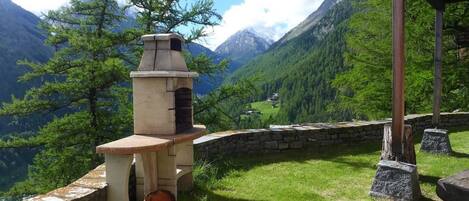 Una parrilla de piedra con chimenea, con montañas al fondo.
