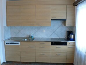 A kitchen with wooden cabinets, a dishwasher, a sink, and a kettle. - Chalet Saasia Appartement/Fewo 9-Bettwohnung by Interhome (Saas-Fee)