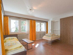 Ein Zimmer mit zwei Betten, einem Tisch und einem Heizkörper.