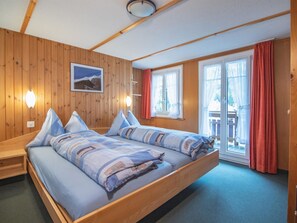 A wooden-paneled room with a large bed, a picture on the wall, and a window with curtains. - Chalet Alpenruh Appartement/Fewo Nr. 2 Mittaghorn by Interhome (Saas-Fee)