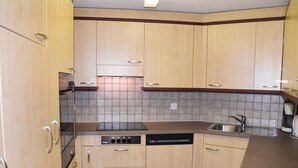Una cocina con armarios de madera, lavavajillas y estufa.