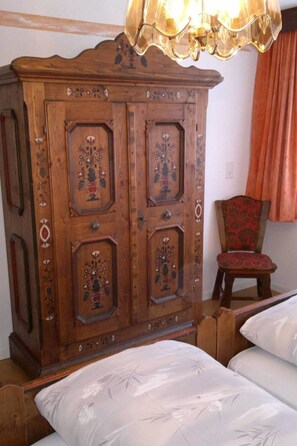 Un mueble de madera con intrincados grabados y una silla con tapicería estampada.