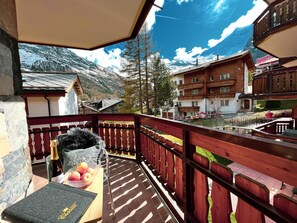 Un balcon avec une balustrade en bois, une bouteille de vin et un saladier de fruits.