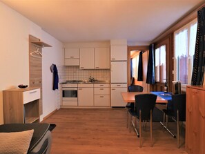 A compact kitchen with a dining area, wooden cabinets, and a small table with chairs. - Chalet Ideal Appartement/Fewo 3-Bettwohnung Nr. 3 by Interhome (Saas-Fee)