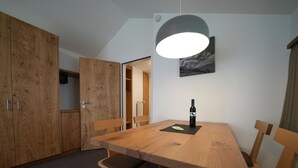 Ein Essbereich mit Holztisch, Stühlen, einer Weinflasche und einer Pendelleuchte.