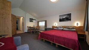 Ein Hotelzimmer mit einem Bett, einem Schreibtisch, einem Stuhl und einem Esstisch.