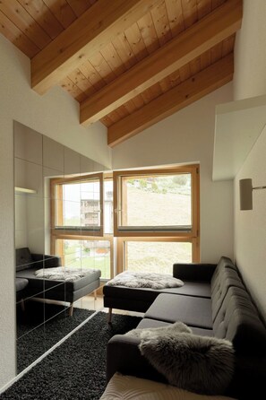 A modern room with a wooden ceiling, large windows, a sofa, and a mirrored wall. - Penthouse Victoria’s Home im Haus Judith Appartement/Fewo Appartement/Fewo by Interhome (Saas-Fee)