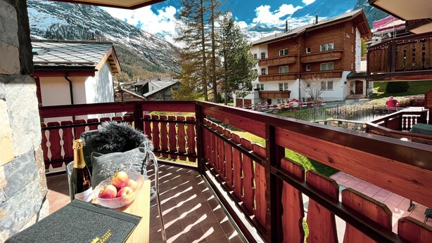 A balcony with a wooden railing, a bottle of wine, and a bowl of fruit. - Residence Chateau Appartement/Fewo 4-Bettwohnung Alphubel A 33 by Interhome (Saas-Fee)