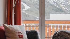 A room with a view of a snowy mountain, a red curtain, a white pillow with a red emblem, and a fur throw. - Residence Chateau Appartement/Fewo 4-Bettwohnung Alphubel A 33 by Interhome (Saas-Fee)