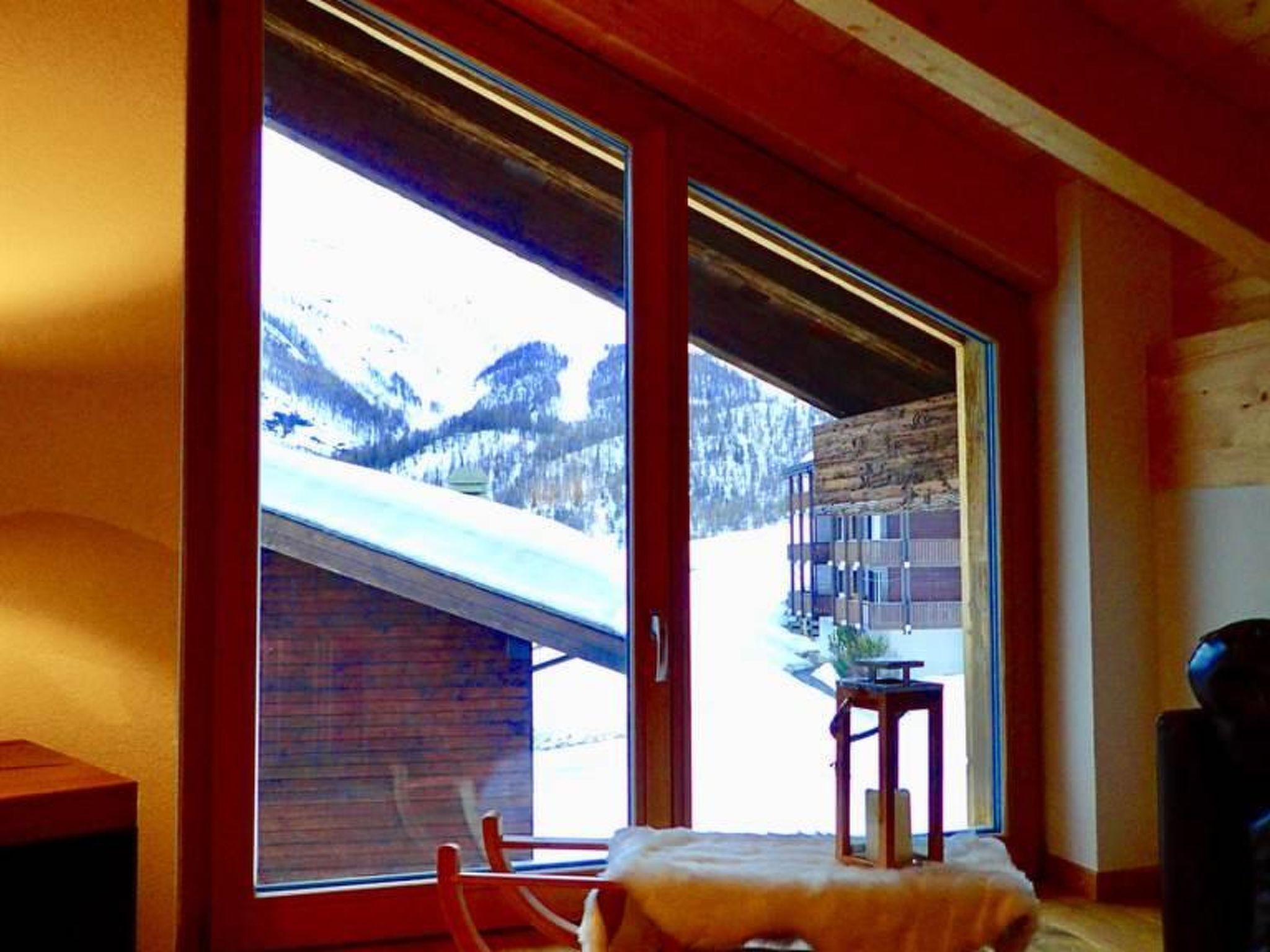 A room with a large window, a wooden table, and a chair.
