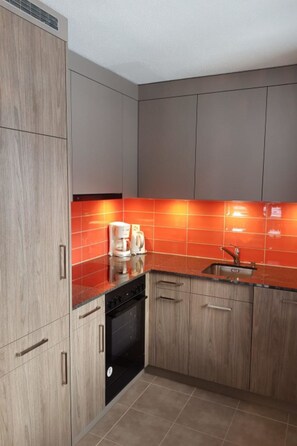 Eine moderne Küche mit Holzausstattung, einem schwarzen Geschirrspüler und einer roten Spritzschutzwand.
