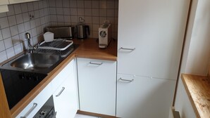 Een kleine keuken met een spoelbak, fornuis, broodrooster, waterkoker en een koelkast.