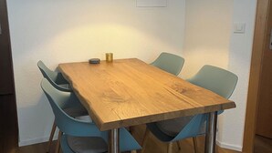 Een houten eettafel met vier stoelen, een hanglamp en een klein decoratief voorwerp op tafel.