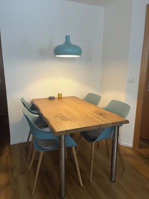 A wooden dining table with four chairs, a pendant light, and a small decorative item on the table. - Achat Appartement/Fewo 4-Bettwohnung Nr. 3 by Interhome (Saas-Fee)