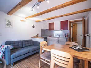 A cozy living area with a sofa, chairs, a dining table, and a kitchen with cabinets and a sink. - Chalet Alpenruh Appartement/Fewo Nr. 4 Allalin by Interhome (Saas-Fee)