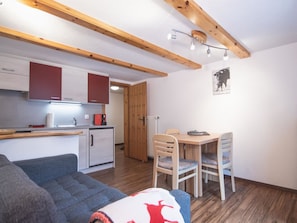 A compact living space with a kitchenette, a dining area, and a seating area with a sofa and chairs. - Chalet Alpenruh Appartement/Fewo Nr. 4 Allalin by Interhome (Saas-Fee)