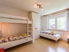 Una habitació amb lliteres, una finestra amb cortines i un lluminari al sostre.