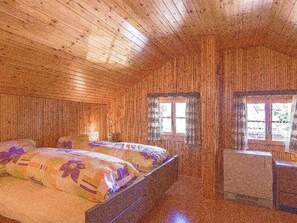 A wooden cabin room with a bed, two bedside tables, and two windows. - Chalet Antika Appartement/Fewo 5-Bettwohnung by Interhome (Saas-Fee)
