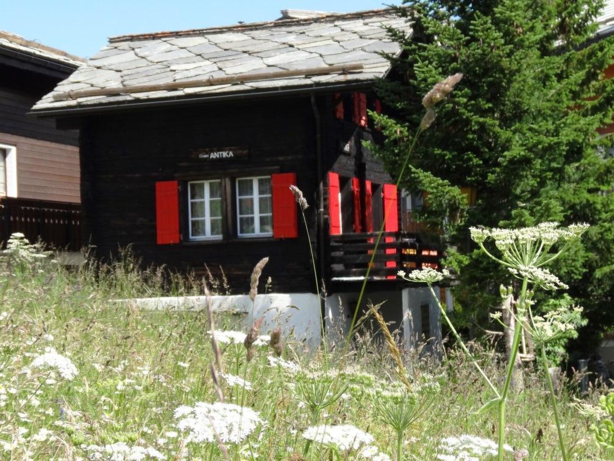 Un bâtiment rustique en bois, doté d’un toit en pente, d’un petit porche et d’une enseigne sur laquelle on peut lire « ANTIKA ».