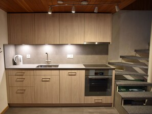 A modern kitchen with wooden cabinets, a stainless steel sink, and a built-in oven. - Chalet Antika Appartement/Fewo 5-Bettwohnung by Interhome (Saas-Fee)