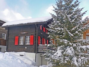 En bygning med et skilt, der viser 'Chalet Antika', og røde skodder.