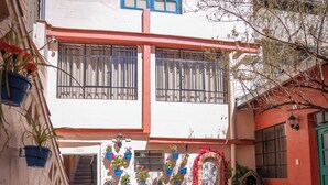 A courtyard with a building featuring a staircase, potted plants, and a tiled floor.