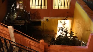 A staircase with a railing, a window with barred glass, and a plant in a corner.