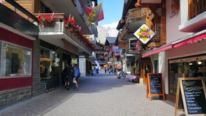 A narrow street with shops and balconies adorned with flowers, a sign for 'Donat Metzger', and a chalkboard menu. - Amedee Appartement/Fewo 5-Bettwohnung Nr. 1 by Interhome (Saas-Fee)